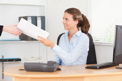 smiling businesswoman receiving a pile of paper
