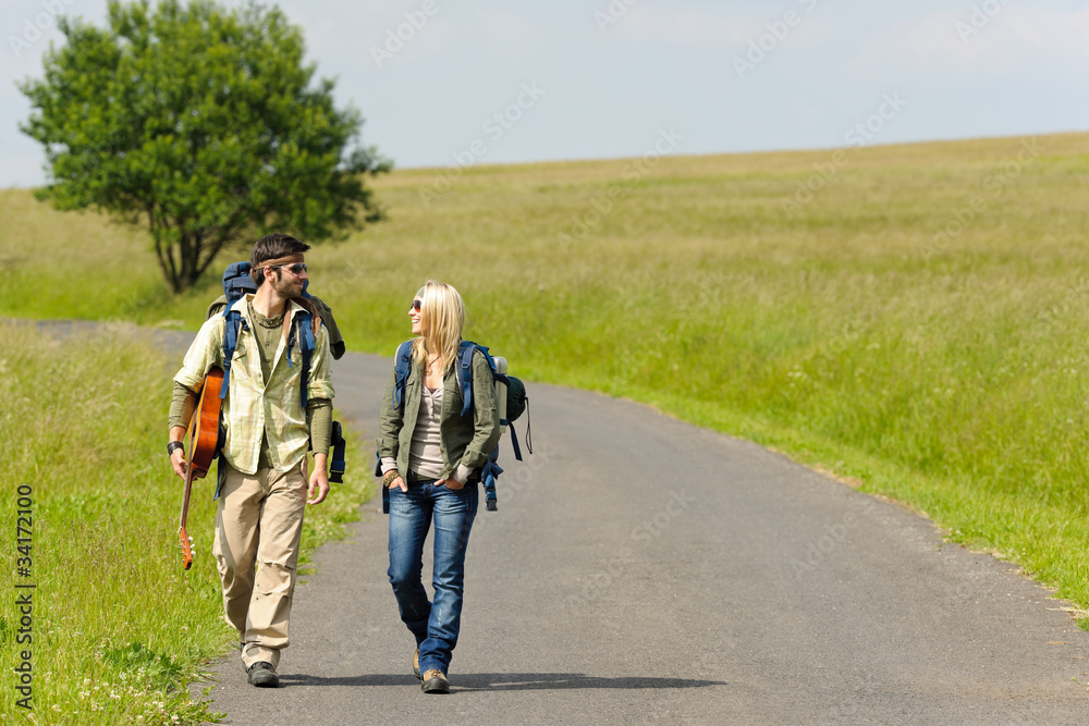 Hiking young couple backpack tramping asphalt road Hiking young couple backpack tramping asphalt road