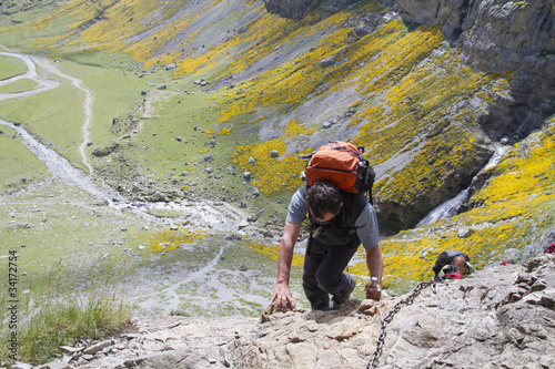 Hombre cruzando un paso complicado en una senda de montaña photo