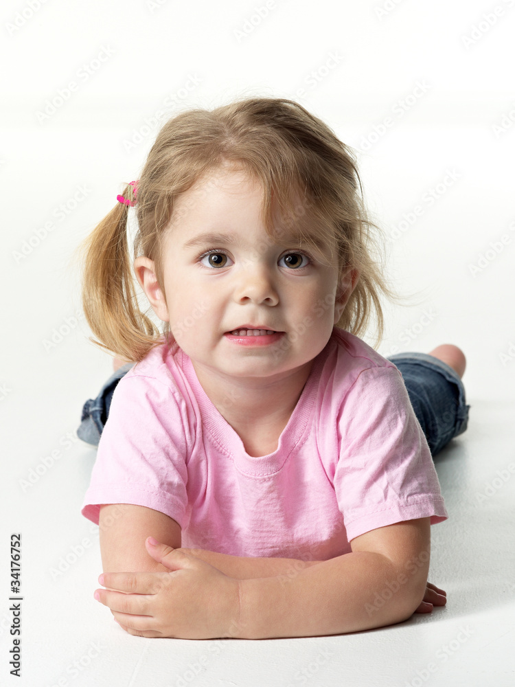 Portrait of adorable little girl lying on the floor