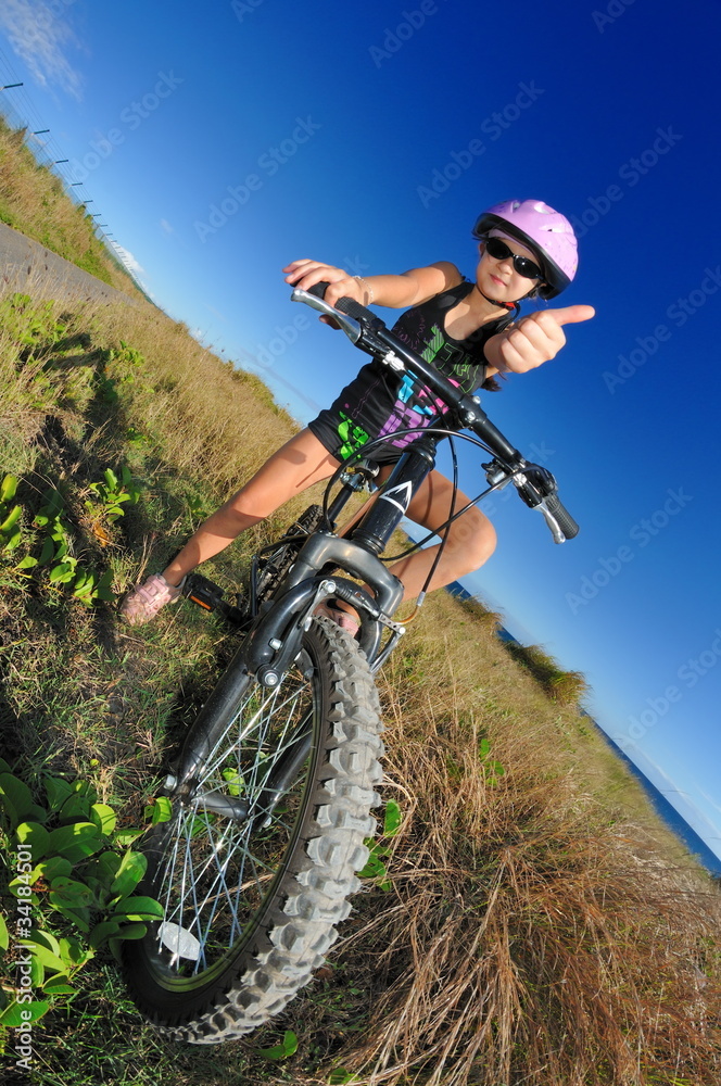 Fillette avec sont vélo dans les herbes.