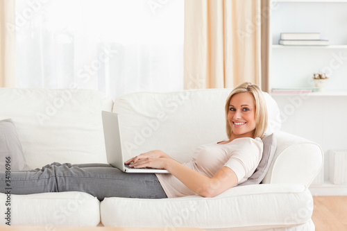 Woman lying on a sofa with a laptop