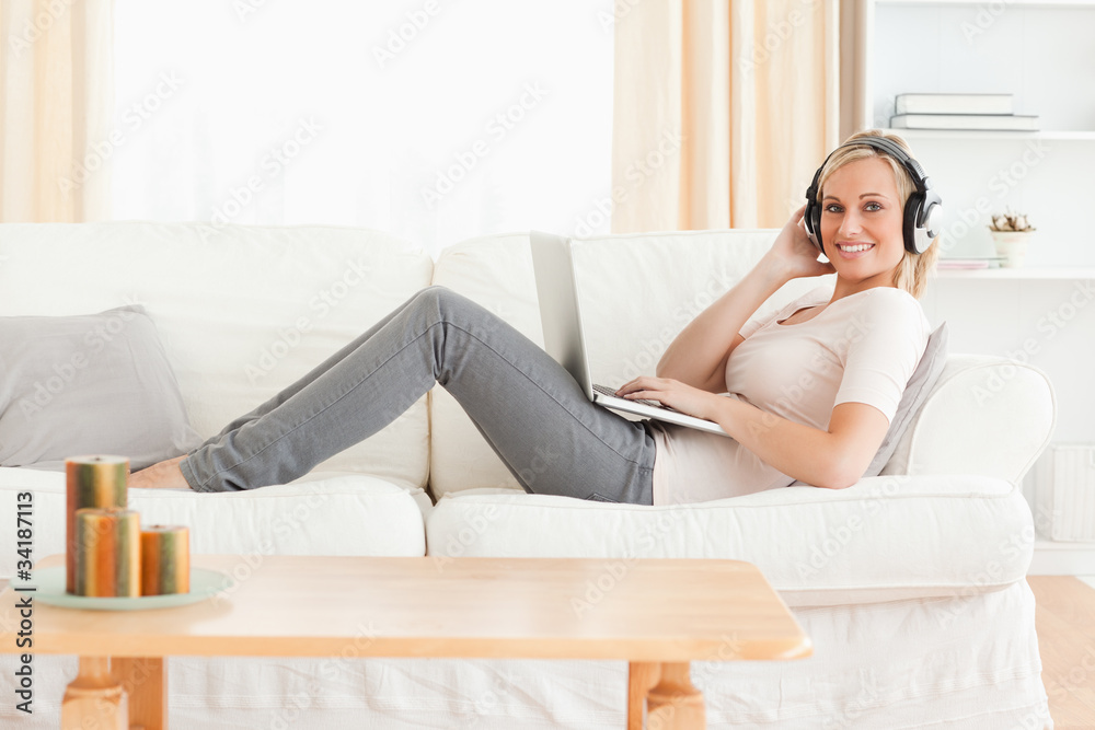 Blond-haired woman with a laptop and headphones Blond-haired woman with a laptop and headphones