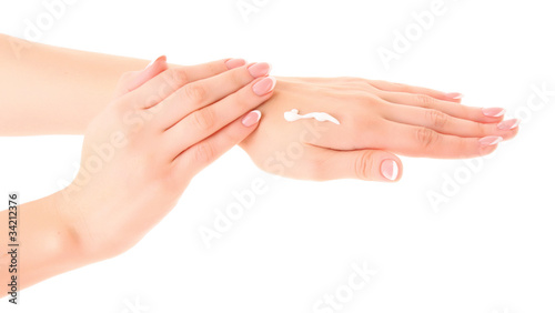 Closeup of beautiful female hands applying hand cream on white