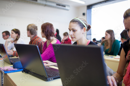 college students sitting in a classroom, using laptop computers