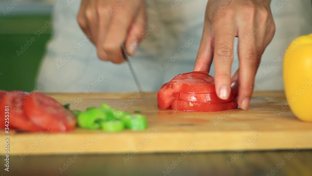 Female hands slicing red tomato Female hands slicing red tomato