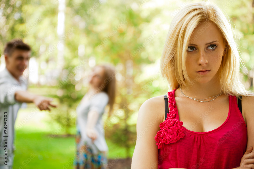 Upset teenage girl being jeered by group of the other young peop Upset teenage girl being jeered by group of the other young peop