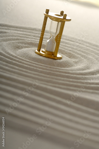 Sanduhr im Sand mit Spuren