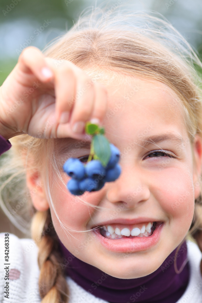 girl holding blueberries in front of her eye smiling girl holding blueberries in front of her eye smiling