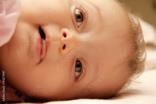 bambina coricata nel lettino sorride photo