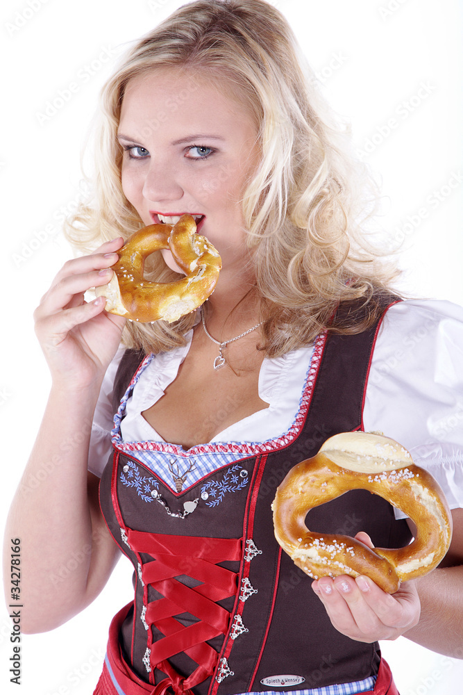 Bayerische Frau im Dirndl beisst in Breze Porträt Bayerische Frau im Dirndl beisst in Breze Porträt