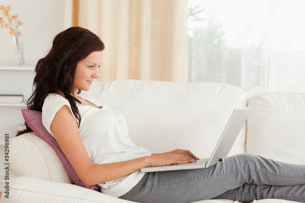 Woman with a laptop lying on a sofa Woman with a laptop lying on a sofa