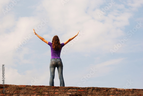 Obraz na płótnie Young woman staying with raised hands against blue sky w salonie
