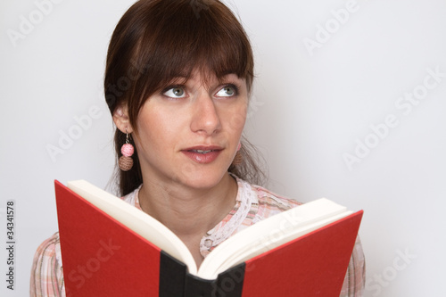 Sweet young brunette reading a textbook, and dreams