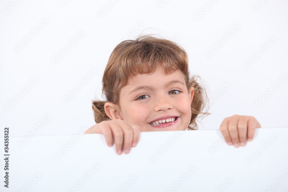 little blonde girl laughing is half hidden behind a white panel little blonde girl laughing is half hidden behind a white panel