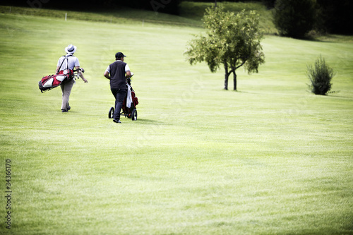 Men walking at golf course with bags.
