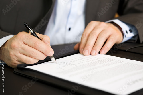 Canvas Print Business person signing a contract, focus on signature.