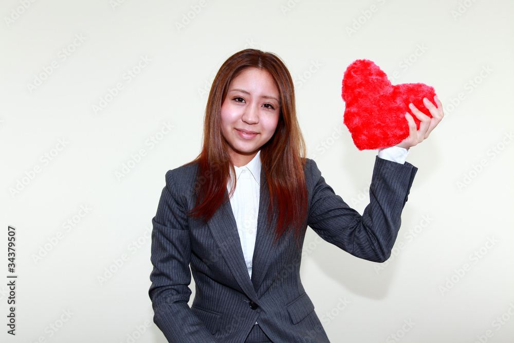 ハートのオブジェを持った笑顔のオフィスレディー