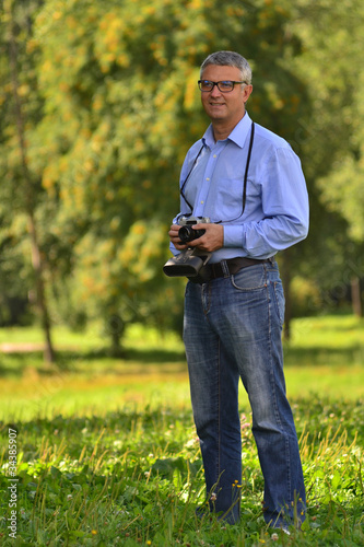 portrait of a man in a park with a camera