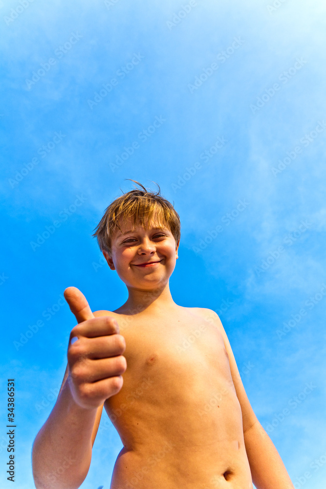 happy smiling young boy gives fingersign all-right, thumbs-up