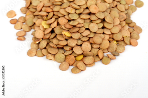 Pile of green lentils from low perspective isolated on white.