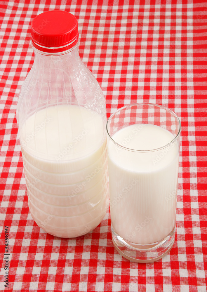 Milk in glass and bottle on checked tablecloth Milk in glass and bottle on checked tablecloth