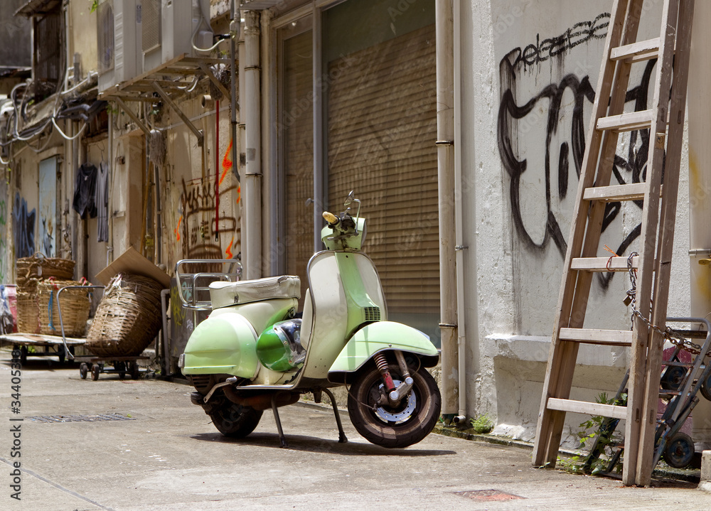 Classic green old scooter in back alley of downtown Hong Kong