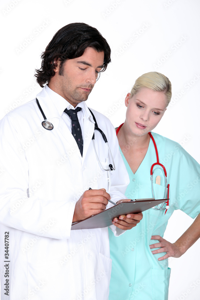 Doctor going over a patient's record with his assistant Doctor going over a patient's record with his assistant