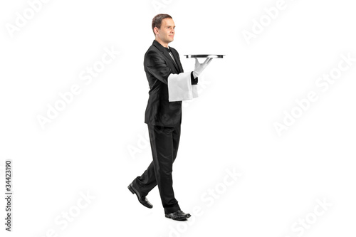 Young butler with bow tie carrying a tray photo