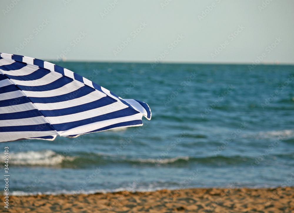 striped umbrella on the beach and sea in the background striped umbrella on the beach and sea in the background
