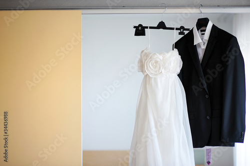 Wedding dress and a tuxedo hanging on a shoulders photo