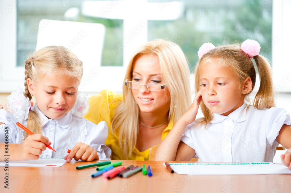 Young pretty teacher helping to her students to make exercise in Young pretty teacher helping to her students to make exercise in
