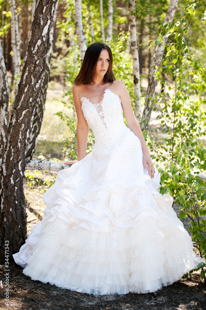 bride with dark-brown hair posing in forest