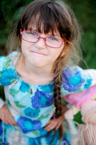 Adorable child girl in glasses makes a funny angry face © Alinute