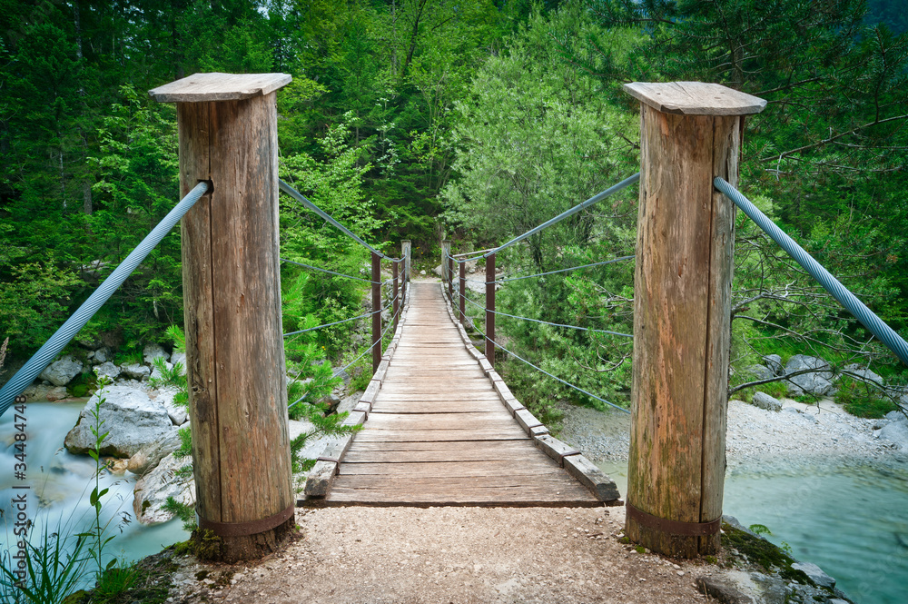Hanging wooden bridge over mountain river in national park.