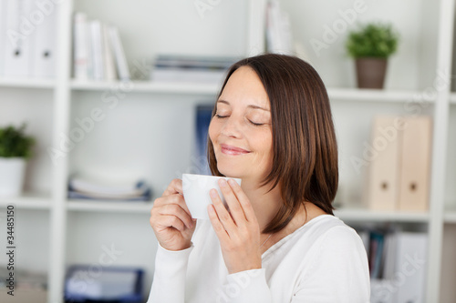 lächelnde frau genießt kaffee im büro