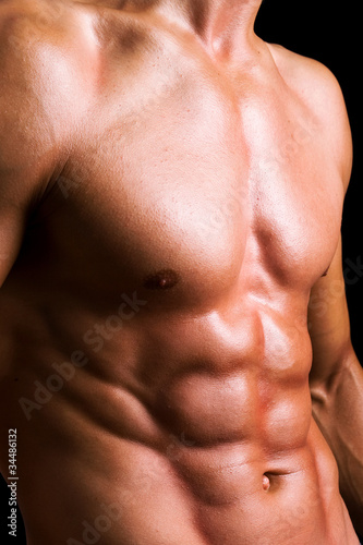 Perfect naked male torso against black background