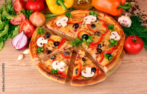 pizza and vegetables on wooden background