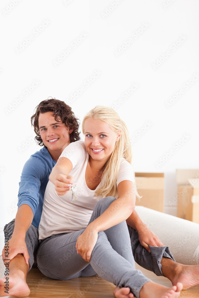 Portrait of a cute woman sitting with her boyfriend giving keys
