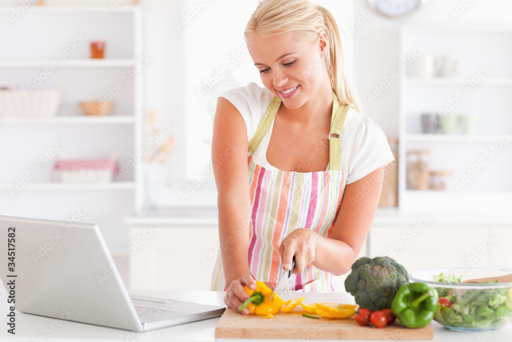 Close up of a blonde woman using a notebook slicing a pepper Close up of a blonde woman using a notebook slicing a pepper