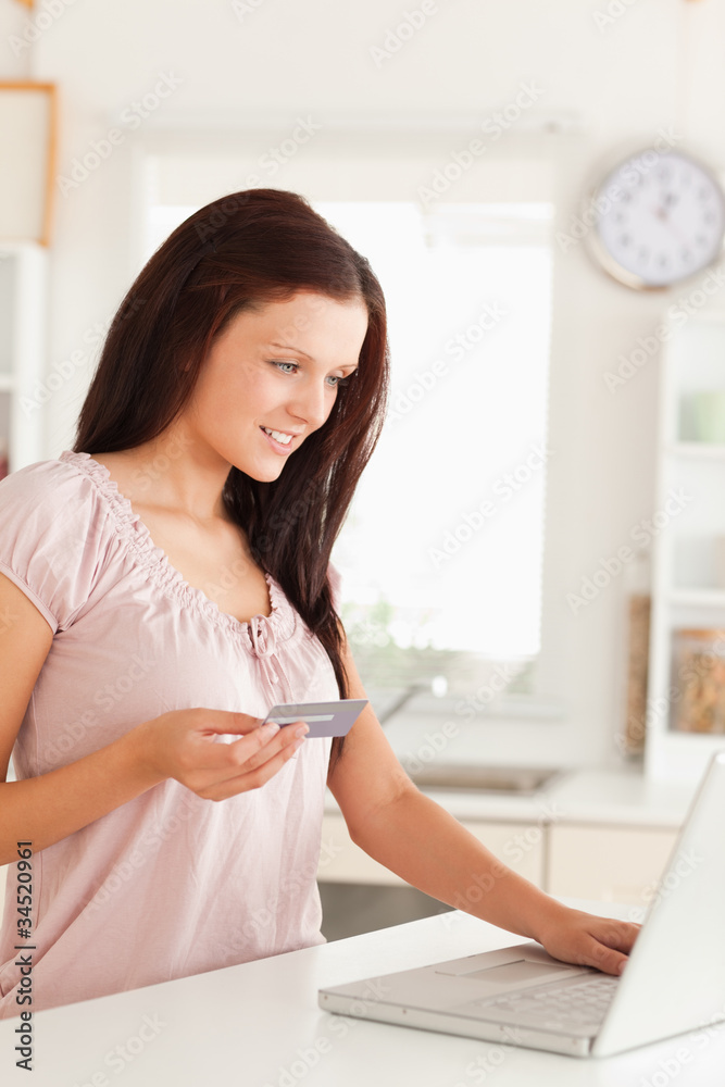 Woman holding credit card and looking at laptop Woman holding credit card and looking at laptop