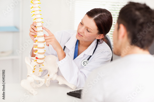Female doctor pointing on bone in spine photo