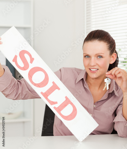 Businesswoman holding keys and sold sign photo