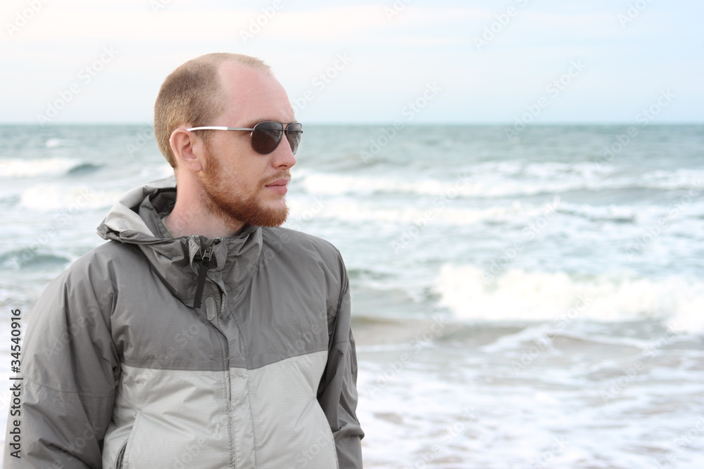 portrait of man with beard in sunglasses near sea