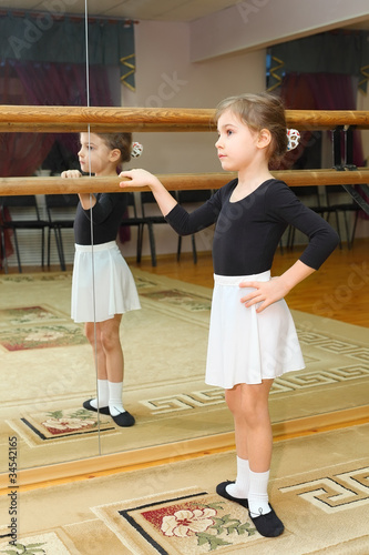 little girl wear pointe in ballet class near frame and mirrror photo