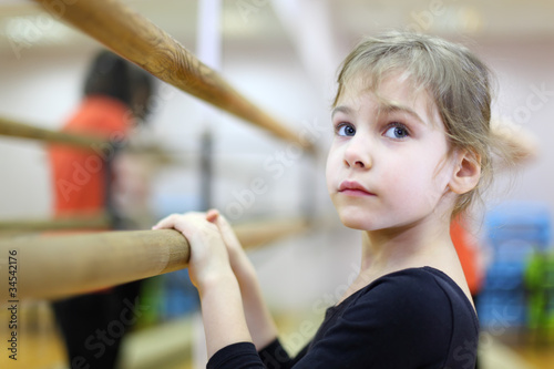 face of little girl in ballet class near frame and large mirror