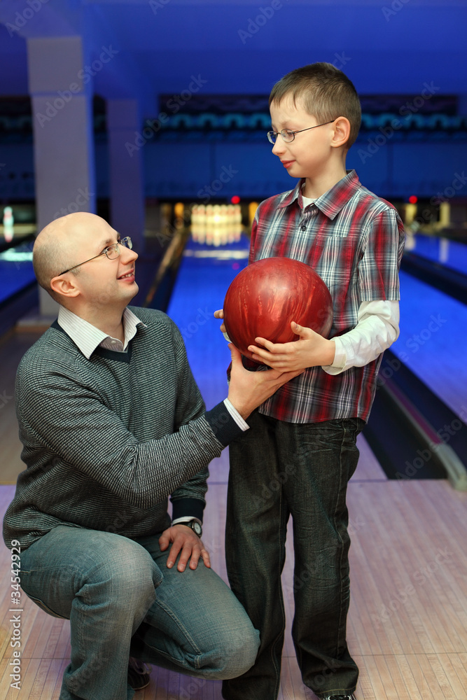 Fototapeta premium Father gives son red ball for bowling