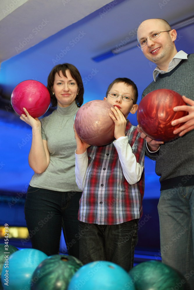Fototapeta premium Family stand alongside and hold balls for bowling