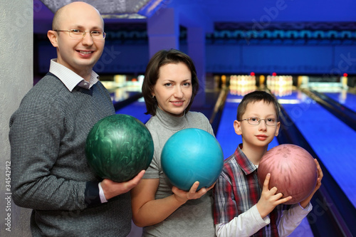 Family stand alongside and hold balls for bowling photo