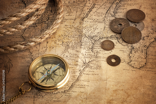old compass, old coins and rope on vintage map